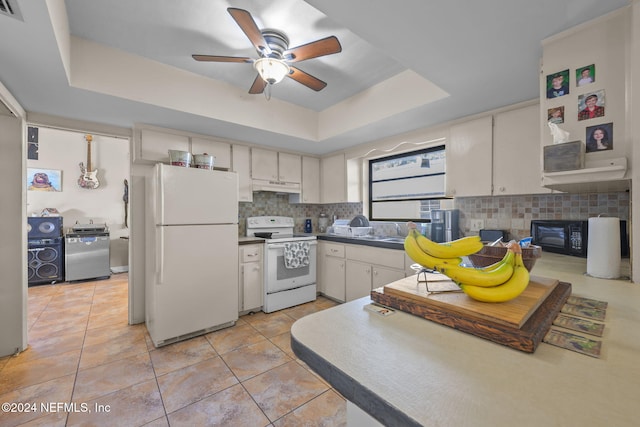 kitchen with white appliances, a raised ceiling, light tile patterned floors, tasteful backsplash, and white cabinetry