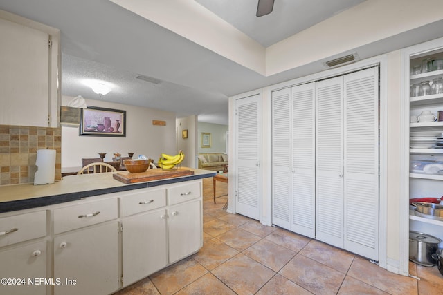 kitchen featuring ceiling fan, white cabinetry, a textured ceiling, and light tile patterned floors