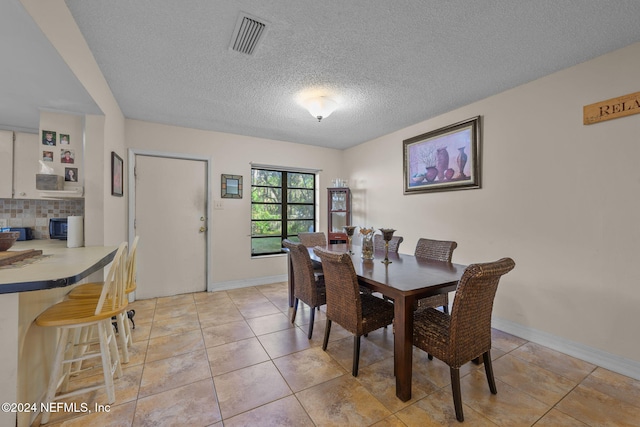 dining area with light tile patterned floors and a textured ceiling