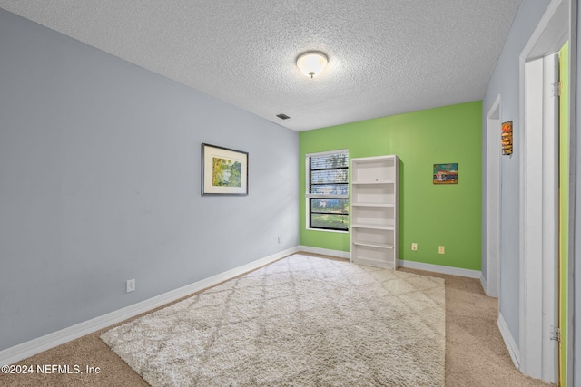 unfurnished bedroom featuring light colored carpet and a textured ceiling