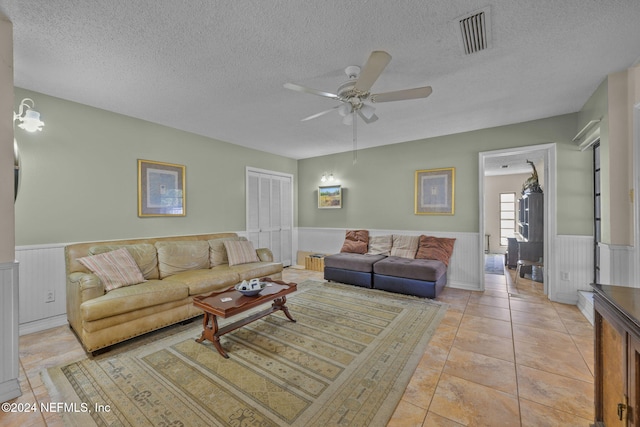 tiled living room with a textured ceiling and ceiling fan