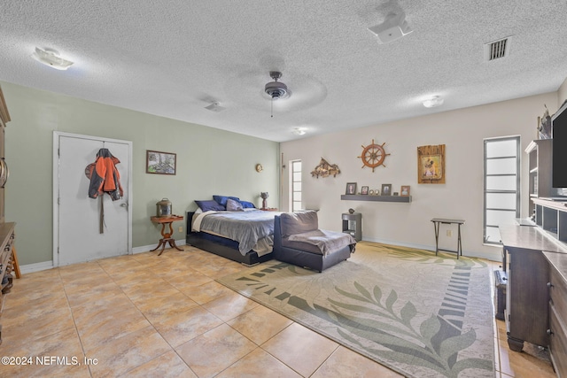 tiled bedroom featuring ceiling fan, a textured ceiling, and a closet