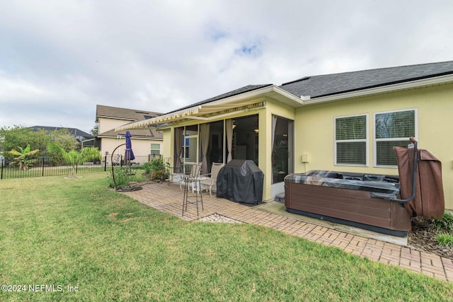 back of house with a patio area, a sunroom, a hot tub, and a yard