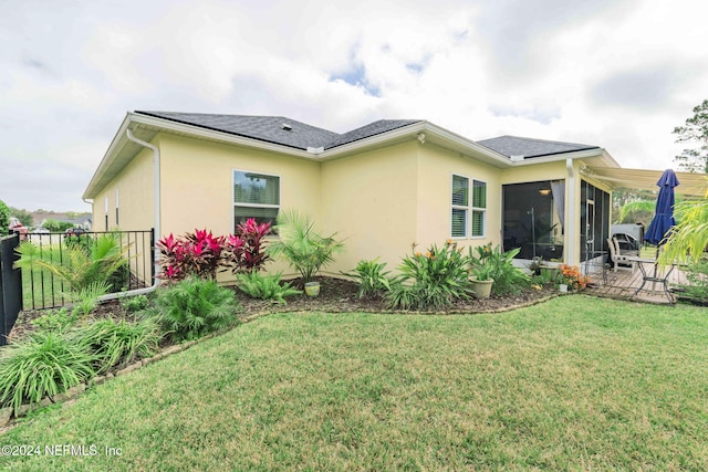 rear view of property featuring a sunroom and a yard