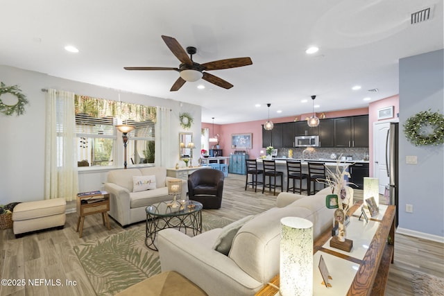 living room with light wood-type flooring and ceiling fan