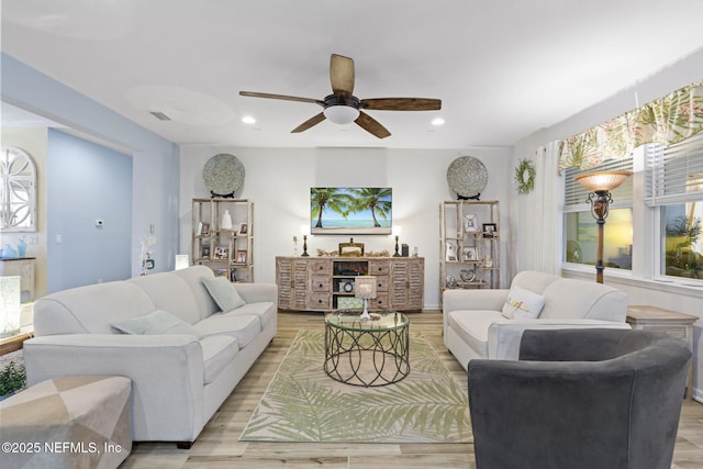 living room featuring light hardwood / wood-style floors, ceiling fan, and plenty of natural light