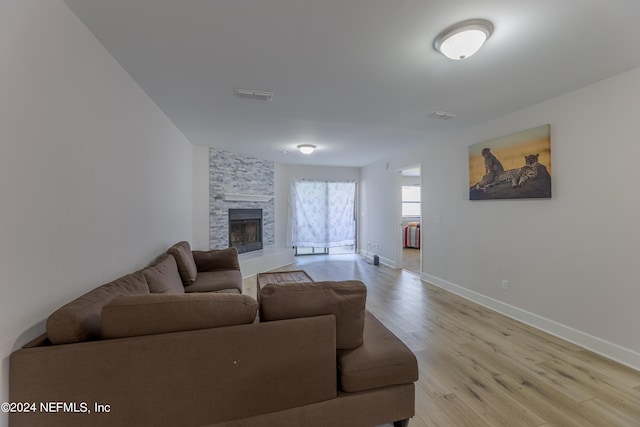 living room featuring light hardwood / wood-style floors and a stone fireplace