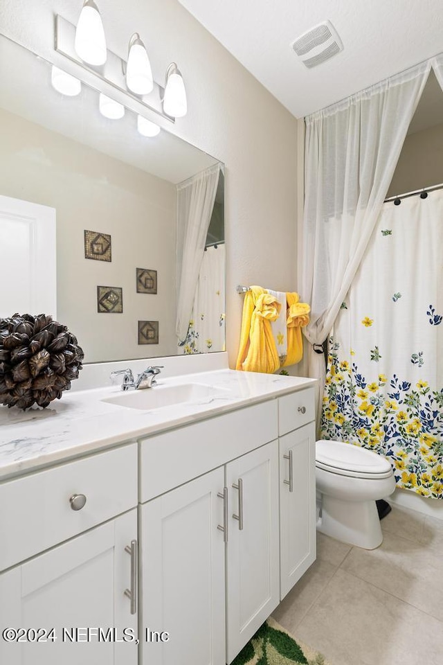 bathroom with toilet, vanity, and tile patterned floors