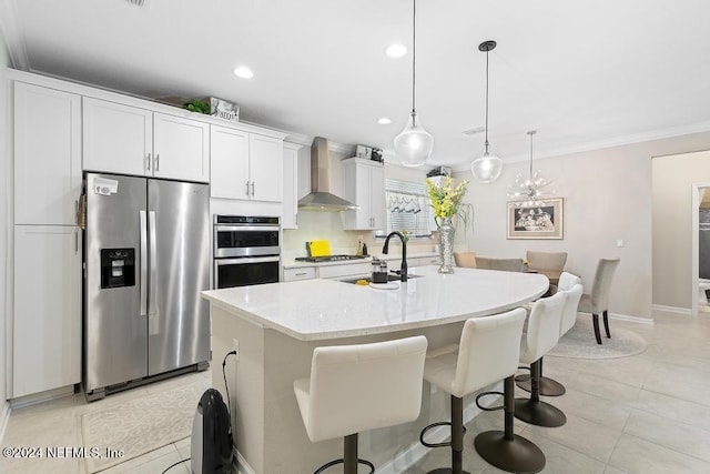 kitchen featuring sink, stainless steel appliances, wall chimney range hood, an island with sink, and white cabinets