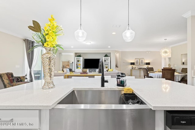 kitchen featuring light stone countertops, a kitchen island with sink, decorative light fixtures, and ornamental molding