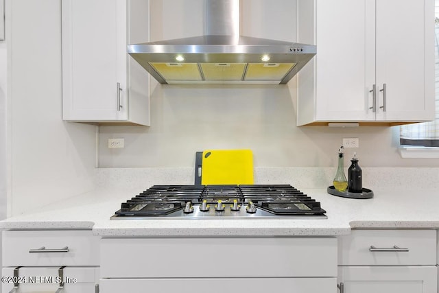 kitchen with stainless steel gas stovetop, light stone countertops, white cabinetry, and extractor fan