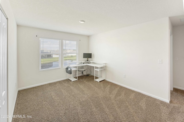 unfurnished office featuring a textured ceiling, baseboards, and carpet flooring