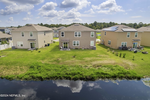 back of house with a water view, a residential view, fence, and a lawn