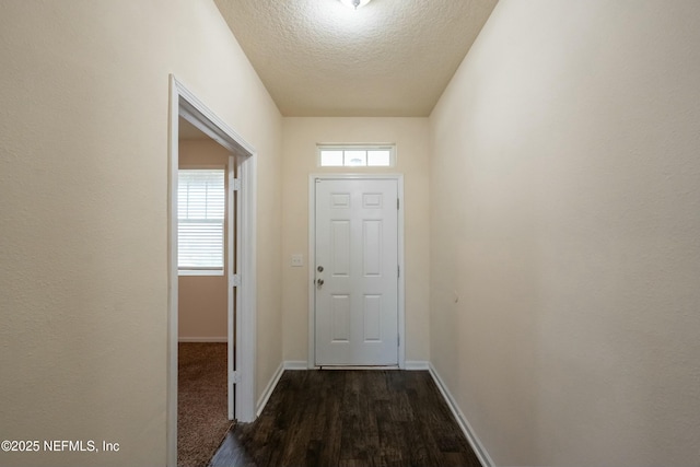 doorway to outside with a textured ceiling, dark wood finished floors, and baseboards