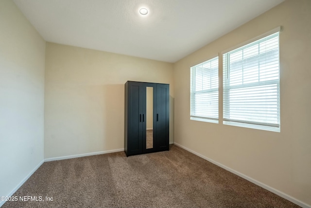 spare room featuring carpet flooring and baseboards