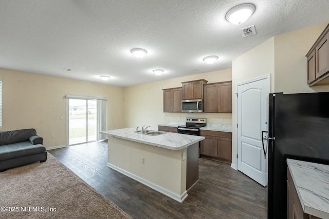 kitchen featuring visible vents, an island with sink, open floor plan, stainless steel appliances, and a sink