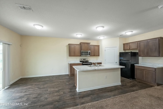 kitchen with visible vents, a kitchen island with sink, stainless steel appliances, light countertops, and a sink