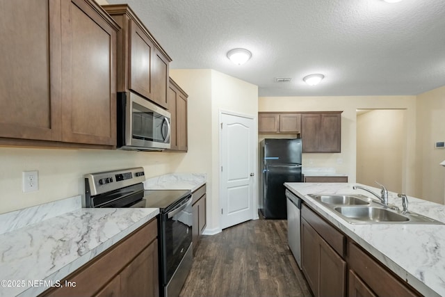 kitchen featuring visible vents, dark wood-type flooring, stainless steel appliances, a textured ceiling, and a sink