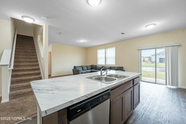 kitchen featuring a center island with sink, light countertops, stainless steel dishwasher, open floor plan, and a sink