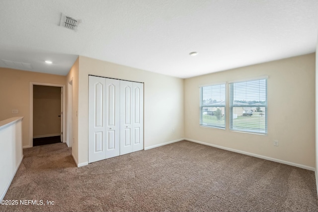 unfurnished bedroom featuring a closet, carpet, visible vents, and baseboards