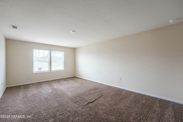 carpeted spare room featuring a textured ceiling, visible vents, and baseboards