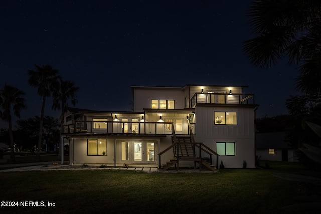 back house at twilight with a yard and a balcony