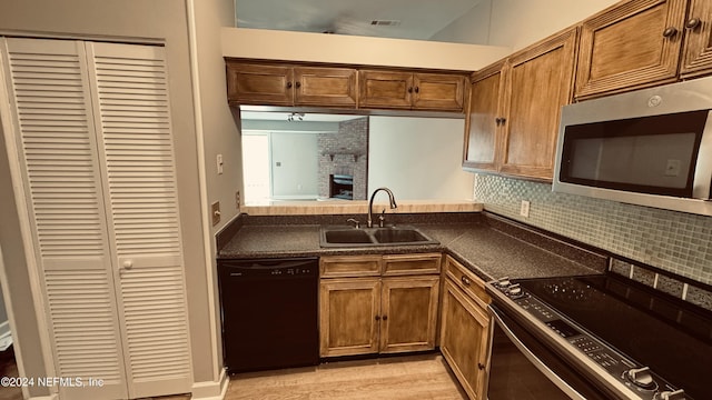 kitchen with appliances with stainless steel finishes, backsplash, light hardwood / wood-style floors, and sink