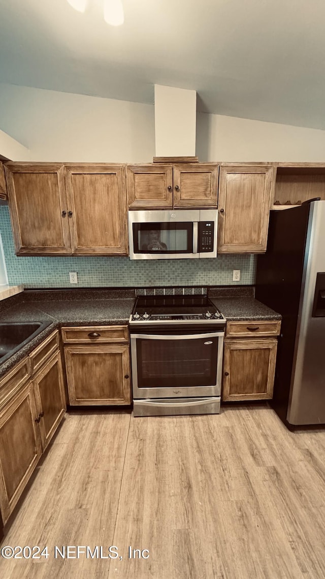 kitchen featuring decorative backsplash, lofted ceiling, appliances with stainless steel finishes, and light hardwood / wood-style flooring