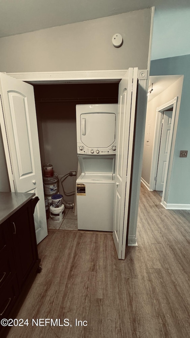 laundry room with light wood-type flooring and stacked washing maching and dryer