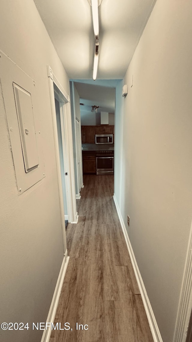 corridor with electric panel and hardwood / wood-style flooring