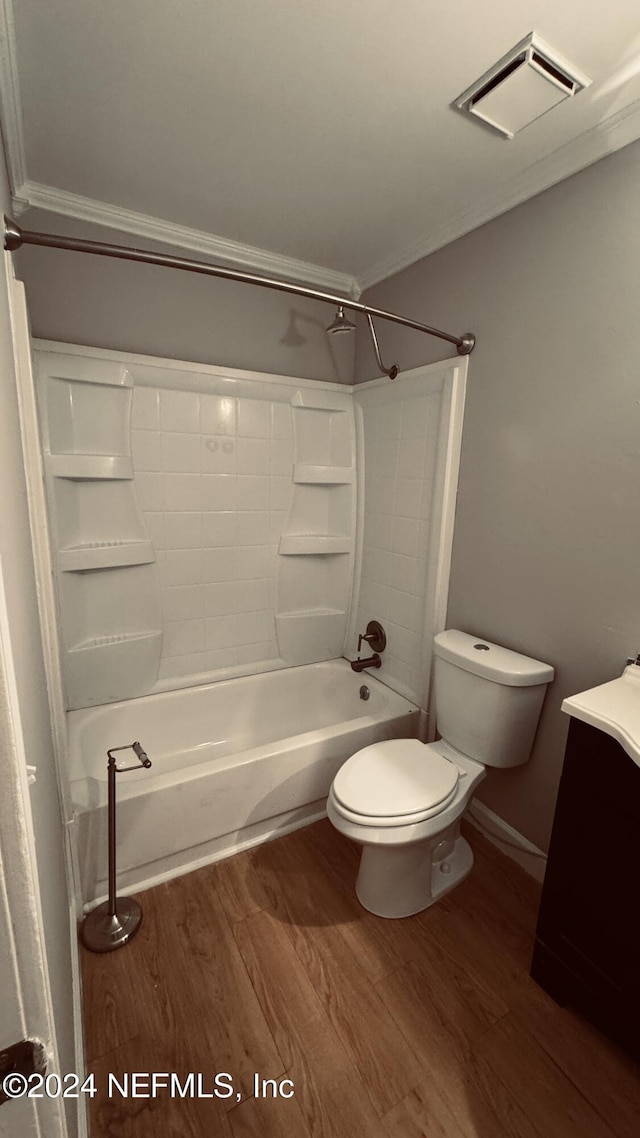 full bathroom with hardwood / wood-style floors, toilet, shower / washtub combination, vanity, and ornamental molding