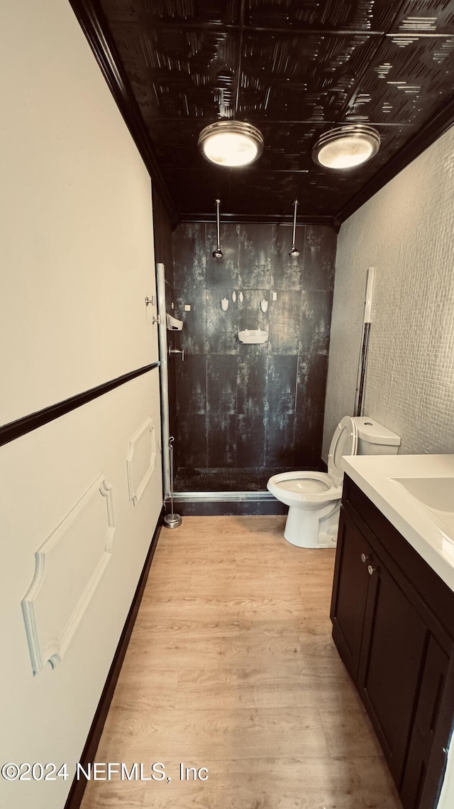 bathroom featuring a shower, crown molding, hardwood / wood-style floors, toilet, and vanity