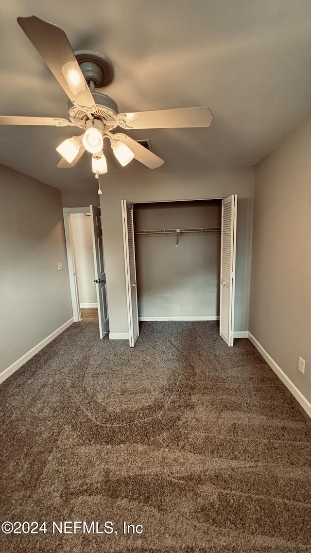 unfurnished bedroom with a closet, dark carpet, and ceiling fan