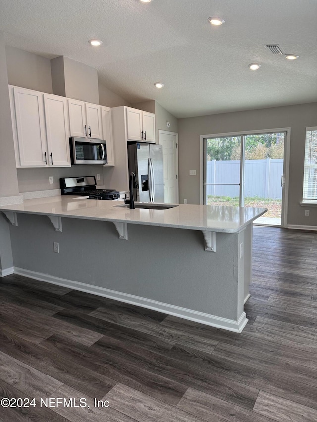 kitchen with kitchen peninsula, white cabinetry, dark hardwood / wood-style floors, and appliances with stainless steel finishes