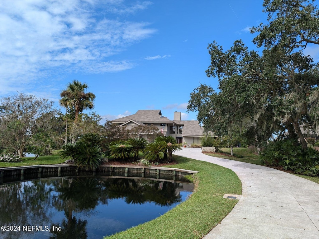 surrounding community with a water view and a lawn