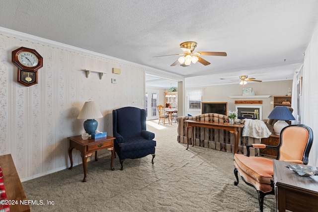 sitting room featuring a textured ceiling, carpet floors, ceiling fan, and crown molding