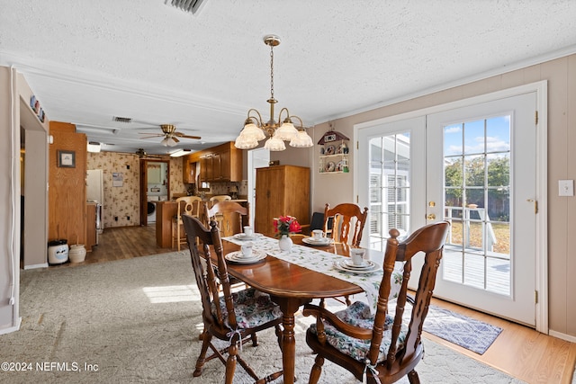 dining area featuring a textured ceiling, ceiling fan with notable chandelier, light hardwood / wood-style floors, and french doors