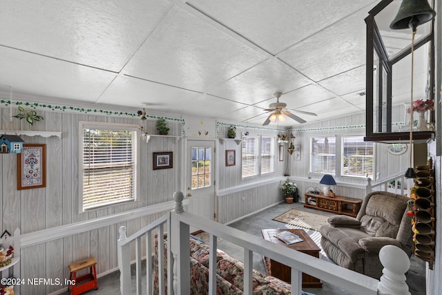 living room with ceiling fan and wood walls