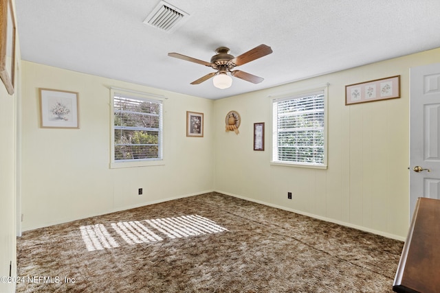 spare room featuring ceiling fan, a textured ceiling, and dark colored carpet