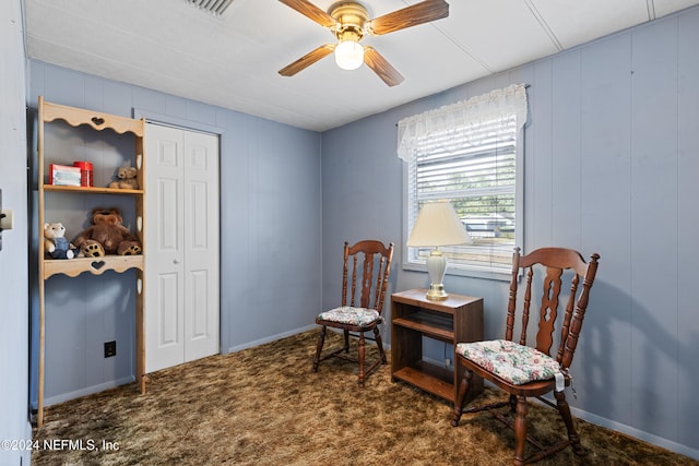 sitting room featuring dark carpet and ceiling fan