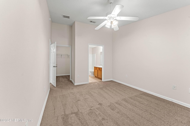 unfurnished bedroom with ensuite bathroom, light colored carpet, ceiling fan, a spacious closet, and a closet