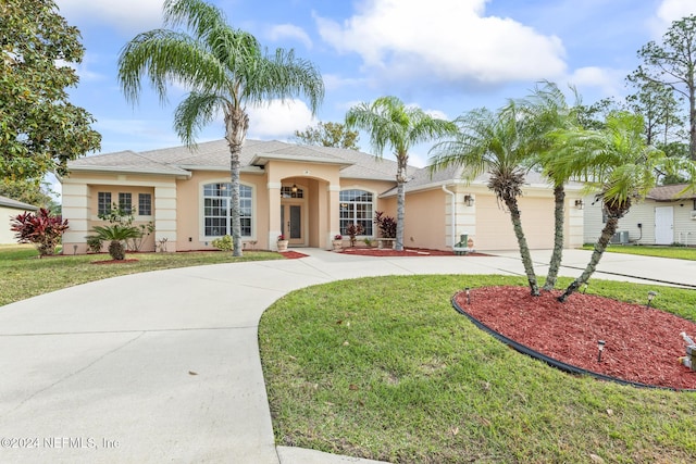 ranch-style home with stucco siding, an attached garage, a front lawn, and curved driveway