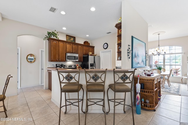 kitchen with visible vents, open shelves, arched walkways, appliances with stainless steel finishes, and a kitchen bar