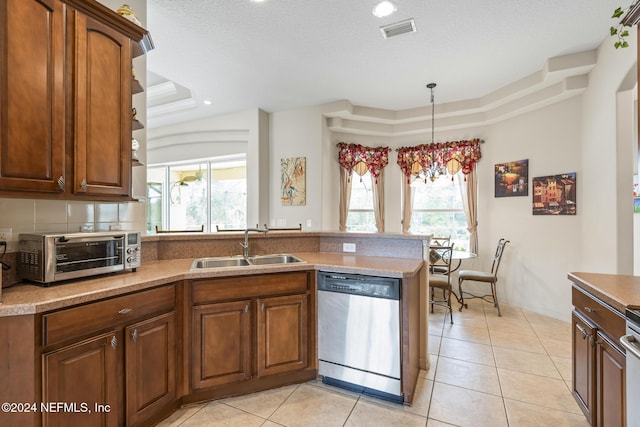 kitchen with visible vents, a sink, a tray ceiling, stainless steel dishwasher, and a peninsula