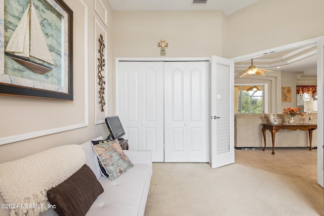 living area featuring light carpet, visible vents, a ceiling fan, and light tile patterned flooring