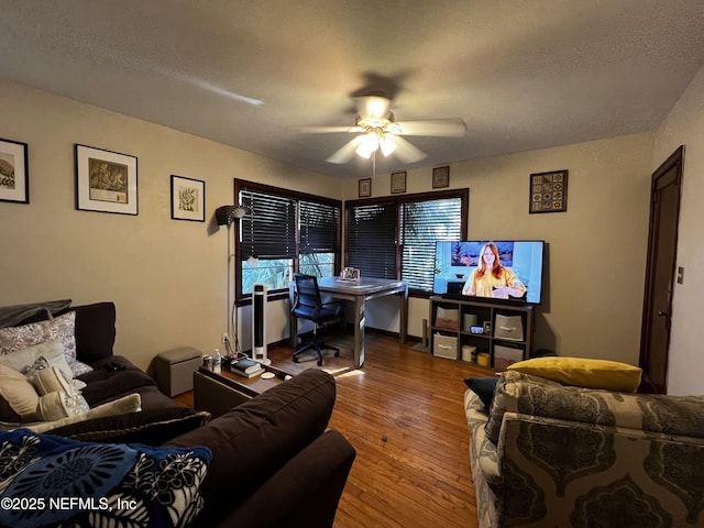 living room with ceiling fan, wood-type flooring, and a textured ceiling