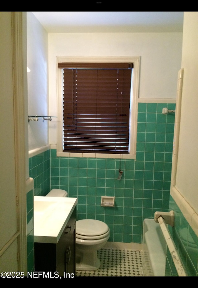 bathroom featuring tile patterned flooring, vanity, toilet, and tile walls