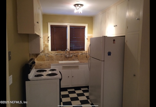 kitchen with white appliances, backsplash, white cabinetry, and sink