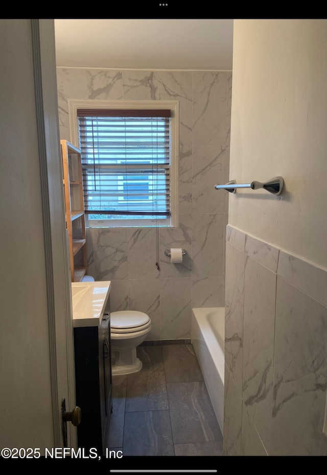 bathroom with vanity, tile walls, and toilet