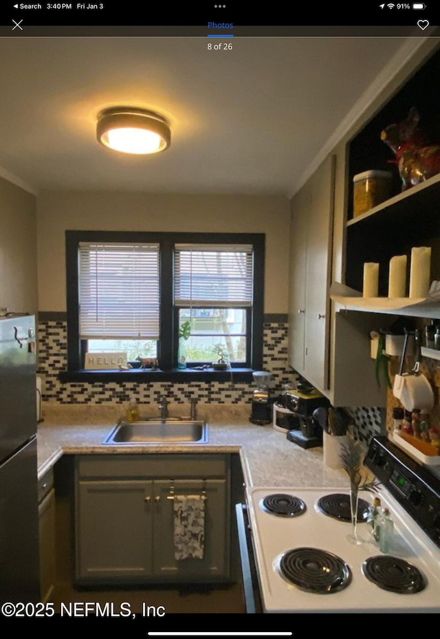 kitchen featuring decorative backsplash, white electric range oven, sink, gray cabinets, and stainless steel refrigerator